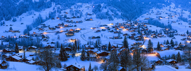 Panorama view of Grindelwald villages with wooden chalets on the dreamy slope in cold winter season at the blue hours in Swiss Alps