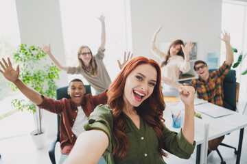 Photo of lucky happy web designers working startup together rising fist taking selfie indoors...