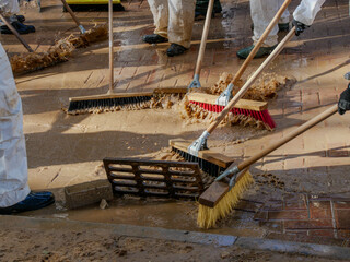 people in white suits, wellies and brushes removing mud, volunteer action, one month after the...