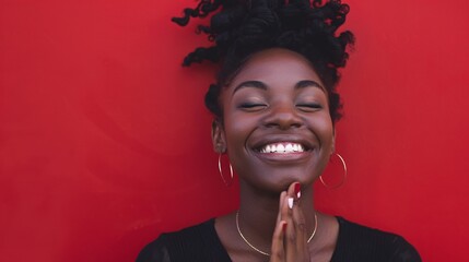 Black woman smiling with relief and gratitude, showing thank you gesture against a red background