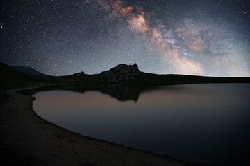 Beautiful night landscape, Bright Milky Way galaxy over the small  lake and mountains. 