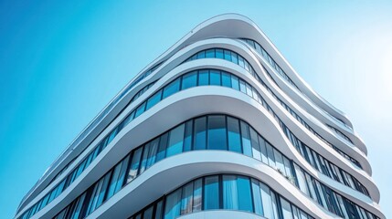 Modern curved glass building against a clear blue sky.