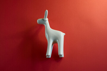 A beautifully stylized white animal figurine stands out vividly against a bright red background