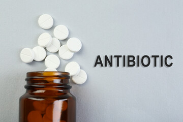 Bottle of antibiotic pills on grey background, top view