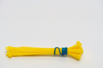 Bundle of Yellow Cable Ties. Close-up of a bundle of yellow cable ties tied together with a blue string, isolated on a plain white background.

