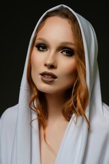 Elegant portrait of a woman wearing a white hooded garment in a studio setting