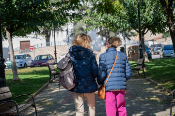 Obraz premium Senior women walking and enjoying a sunny day in a spanish city, rear view