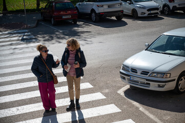 Two women chatting while crossing a street in a small Spanish town