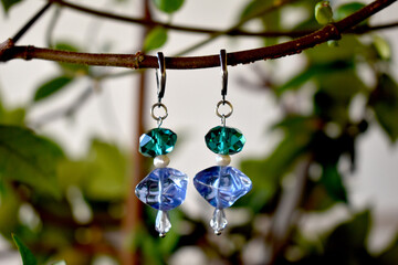 A chic pair of earrings  hanging on a branch.Handmade jewellery.