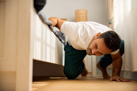 Mid adult man searching for something below his bed.