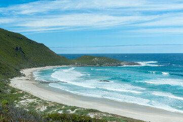 Turquoise waters meet pristine white sand at a secluded beach in Western Australia. Rugged coastline and scattered boulders create a picturesque and tranquil coastal escape.