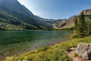 Obraz premium Tranquil lake surrounded by mountains and greenery.