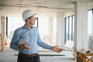 Portrait of an architect builder studying layout plan of the rooms, civil engineer working with...