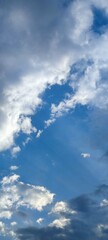 The clouds in sky. In the evening sky there are cumulus and cirrus clouds. They are at different levels, some of them are white, some are gray. The rays of the setting sun are visible behind it.