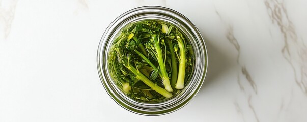 Obraz premium Fresh Broccolini Stalks in a Jar on a White Surface