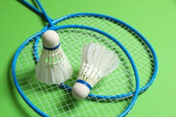 Badminton rackets and white badminton shuttlecocks on color background