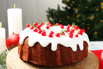 Traditional Christmas cake decorated with red currants and rosemary on table, closeup