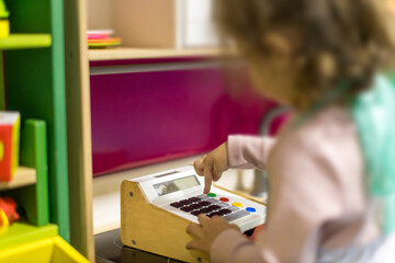 Child plays with a toy cash register in a colorful learning environment during playtime