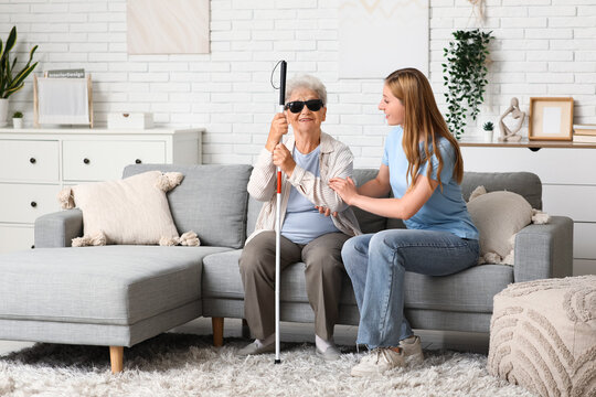 Young woman with blind grandmother sitting on sofa at home