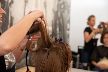 Fototapeta premium A talented hairstylist is diligently working on enhancing a models hair inside a chic salon