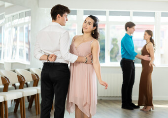 Young man and young woman dance ballroom dance waltz in studio