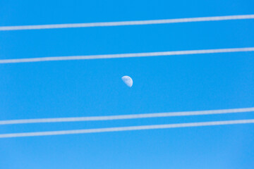 Moon and wires in the blue sky