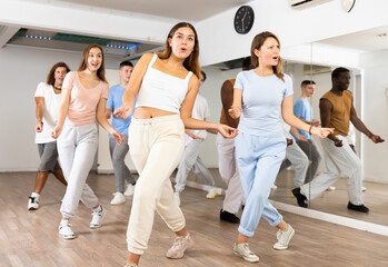 Excited sporty multiracial people practicing new movements steps during dancing training in studio