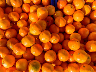 There are a lot of tangerines on the market counter.