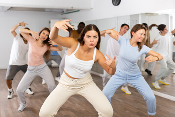Energetic women and man performing modern dance in fitness studio