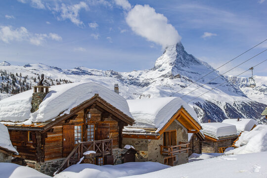 Village Eggen in winter with deep snow covered roofs under the famous Alps landmark Matterhorn, Zermatt, Switzerland
