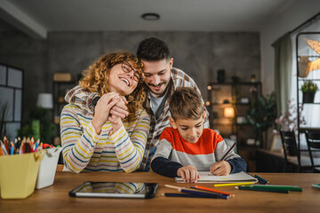 Mum and son paint together, while dad hugs and supports them