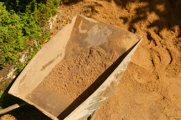 Construction wheelbarrow filled with sand work with a shovel