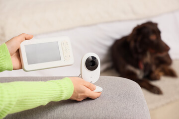 Woman with CCTV camera and video monitor against her dog in bedroom, closeup