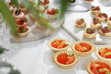 Many different tasty canapes on white wooden table, closeup