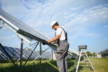 An Indian worker in uniform and with tools works on a solar panel farm