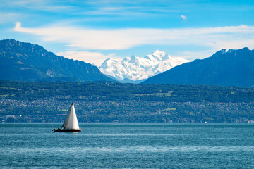 Naklejka premium Sailboat on a Geneva lake with majestic mountains