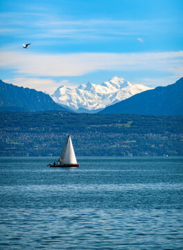 Sailboat on calm Geneva lake with mountain view