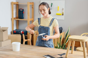 Young woman with putty knives at table in room