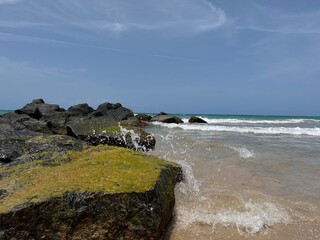 Beach view with water splashing on rocks