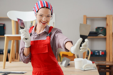 Female decorator with putty knives in room