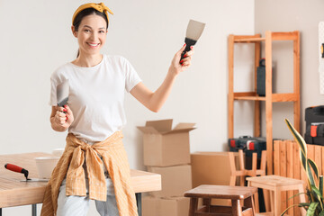 Young woman with putty knives smiling in room