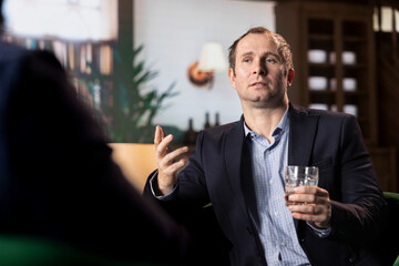 Businessmen in a classic library discuss partnership goals over whiskey, reflecting trust, success...