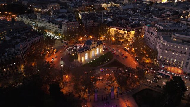 This stunning aerial shot captures the breathtaking beauty of Madrid, showcasing the majestic El Retiro Park, the iconic Puerta de Alcala, and the vibrant lights of the bustling cityscape around them