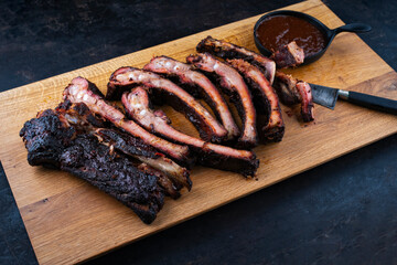 Barbecue spareribs St Louis cut with hot rub and BBQ sauce served as close-up on a wooden design board