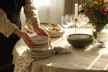 Woman setting table for dinner at home, closeup