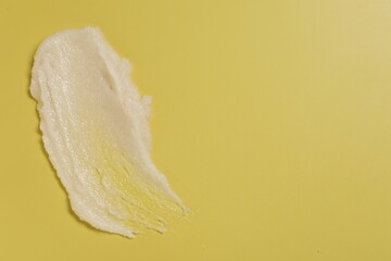 Sample of body scrub on yellow background, top view. Space for text
