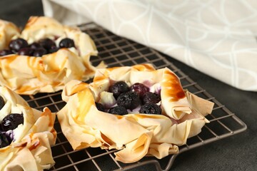 Delicious puff pastries with blueberries on gray textured table, closeup