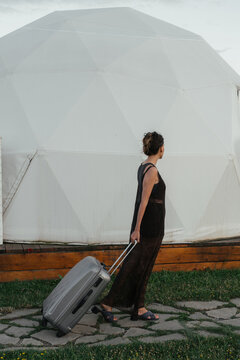 A traveler walking towards a geodesic dome with a suitcase in hand