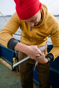 A Man unhooks a Fish on a Boat in the Barents Sea