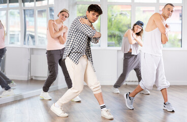 Active young guy practicing basic hip-hop moves in training hall during dancing classes